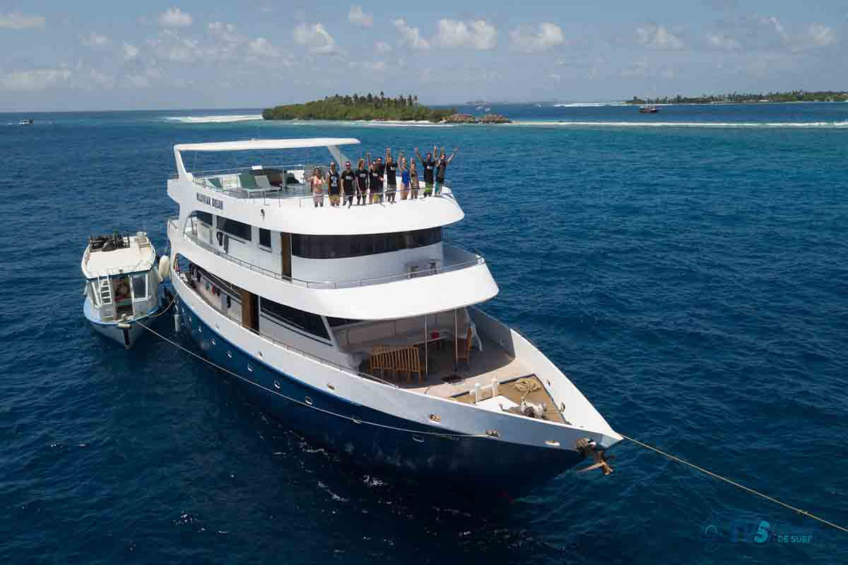 Barco de surf navegando en Maldivas con surfistas a bordo